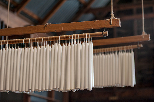 White taper candles hanging after being made