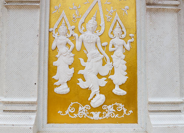 white angel sculpture on golden wall in asian temple