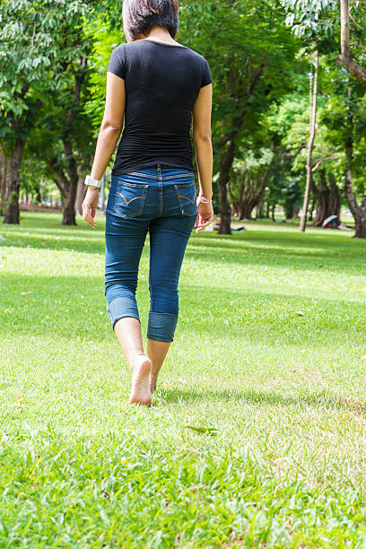 Asian girl legs walking on grass in the green park