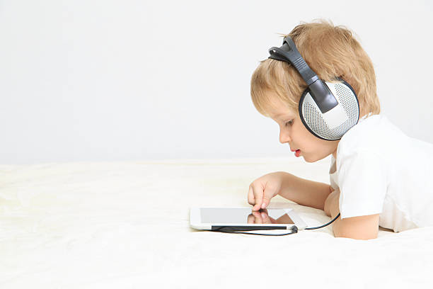 mały chłopiec z słuchawki przy użyciu touchpad - ipad baby boys little boys caucasian zdjęcia i obrazy z banku zdjęć
