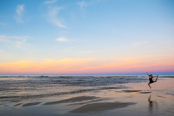 istock Girl dancing across water at sunset 481993274