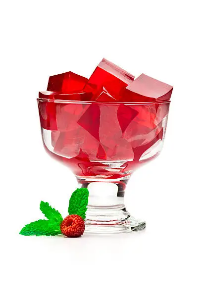 Dessert cup filled with raspberry gelatin cubes isolated on white backdrop.