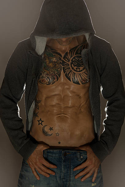 Nice body Muscled tattooed man with sports jacket with hood and light behind chest tattoo men stock pictures, royalty-free photos & images
