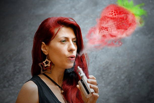 elegante donna fumare una sigaretta elettronica esterna ufficio edificio - smoking women smoke smoking issues foto e immagini stock