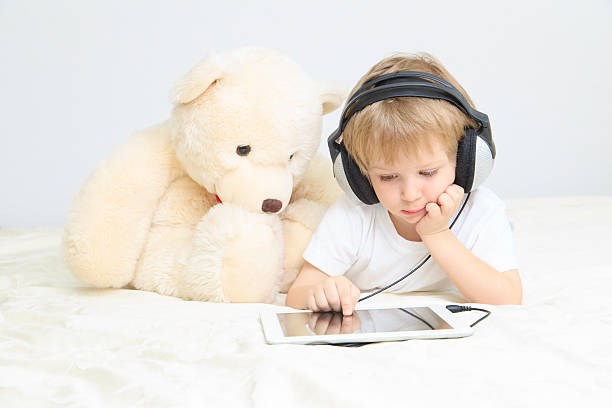 mały chłopiec z słuchawki przy użyciu touchpad - ipad baby boys little boys caucasian zdjęcia i obrazy z banku zdjęć