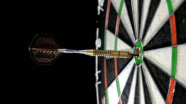 Close up of a single dart hitting the bull's eye on a dart board