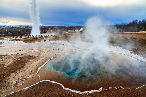 Blue pool at the Haukadalur geothermal area, part of the golden circle route, with the Strokkur Geyser in the background in Iceland
