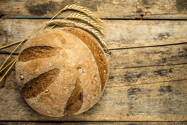 istock Loaf of whole wheat bread with ears on wood background 482028882