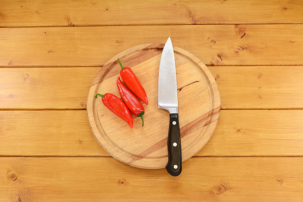 istock Three red peppers with a knife on a chopping board 482029444