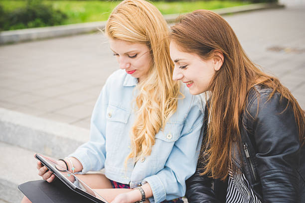 istock Two young girl seated on the ground using a tablet 482034184