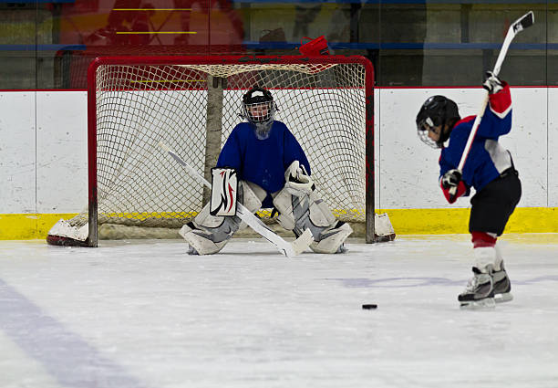 joueur de hockey sur glace des pousses le palet au but - fitness goal photos et images de collection