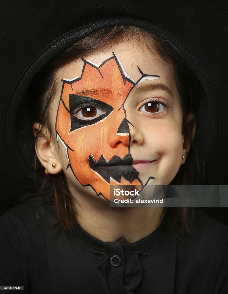 Pretty girl with face painting of a pumpkin Pretty girl with face painting of a pumpkin isolated on black background Art Stock Photo