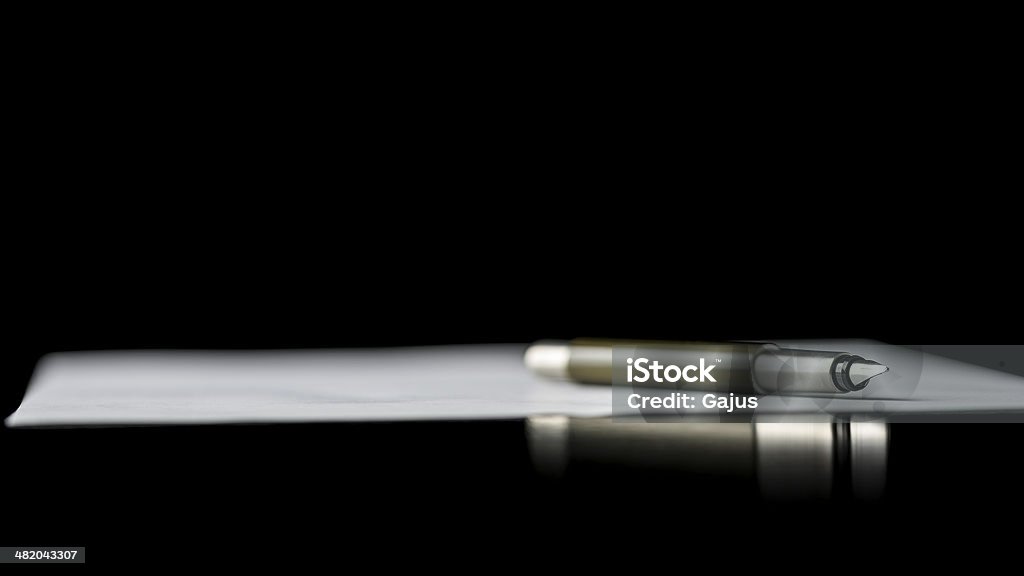 Fountain pen lying on a document Fountain pen lying on a document depicting writing a letter, taking notes or signing a document, isolated over black background. Contract Stock Photo