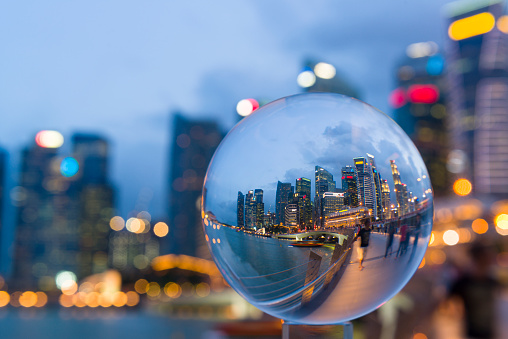 Reflection of Jubilee Bridge and Central Business District of Singapore during dusk hour in a glass ball, tourists enjoy the night scene at Jubilee Bridge.