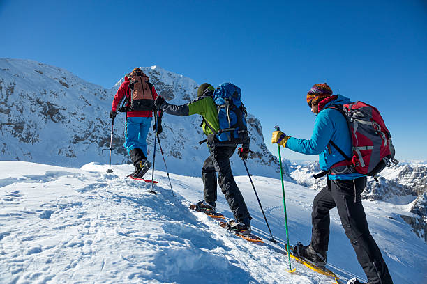 Men hiking on snow covered landscape Julian Alps, Triglav National Park, Three hikers snowshoeing on snow covered mountain peak. snowshoeing snow shoe red stock pictures, royalty-free photos & images