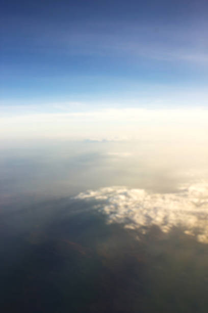 Abstract and blur background of blue sky with cloudy over mountain from window airplane view. Sunset light.