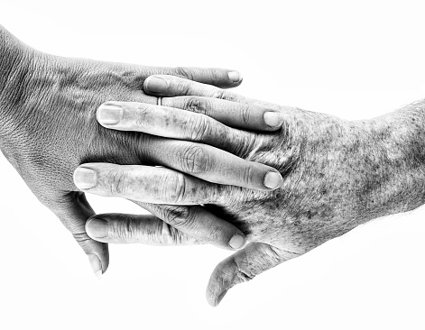 Black and white image of mature people holding hands. Filtered image.