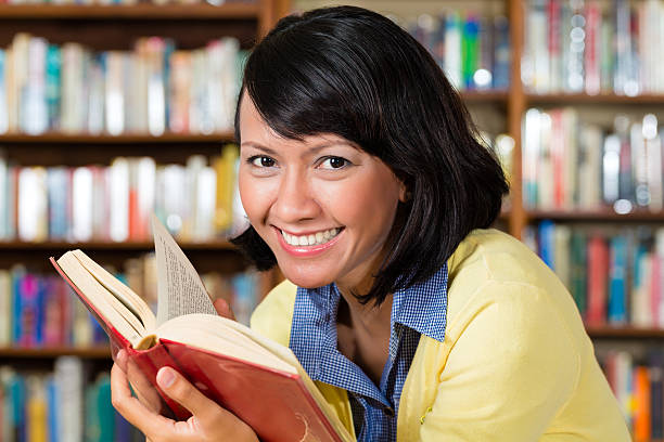 istock Asian girl in library reading a book 482057657