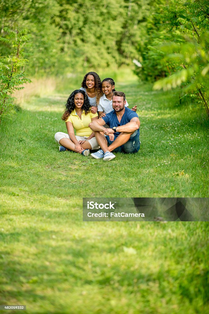 Family at the Park A multi-ethnic family with mixed race children spending quality time together outdoors in nature at a park - posing for a family photo. Multiracial Group Stock Photo