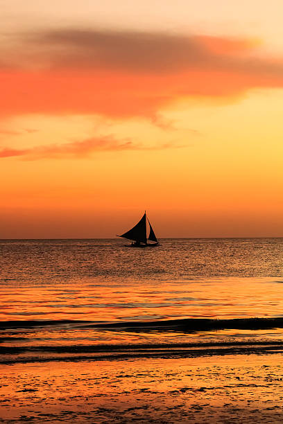 istock Firey orange sky reflected in calm ocean with sailboat silhouette 482062631