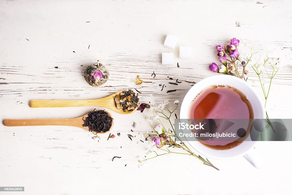A teacup surrounded by flowers and tea leaves A cup of tea with flowers and tea around it Breakfast Stock Photo