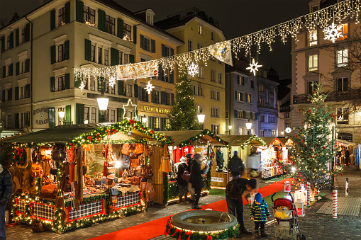 Zurich, Switzerland - December 11, 2014: People at one of the Christmas markets of Zurich. The city welcomes visitors with 5 traditional markets scattered in various locations of the Old Town, with stalls of gifts, crafts, sweets and mulled wine.