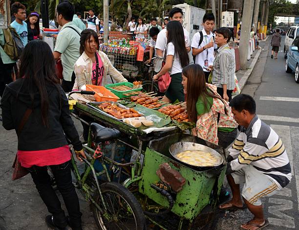 Skewer seller in Manila Manila, Philippines - January 23, 2014: Skewer seller in a very crowded area of manila downtown. Some girls helping him to move the ambulant stall. philippines tricycle stock pictures, royalty-free photos & images