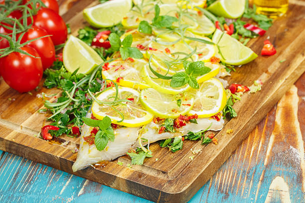 Cilantro Lime Cod  Cod fillet with chili and limes. Macro, selective focus tarragon cutting board vegetable herb stock pictures, royalty-free photos & images