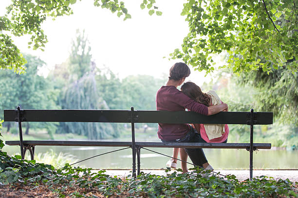 istock Romantic young couple sitting on bench at lakeside 482074687