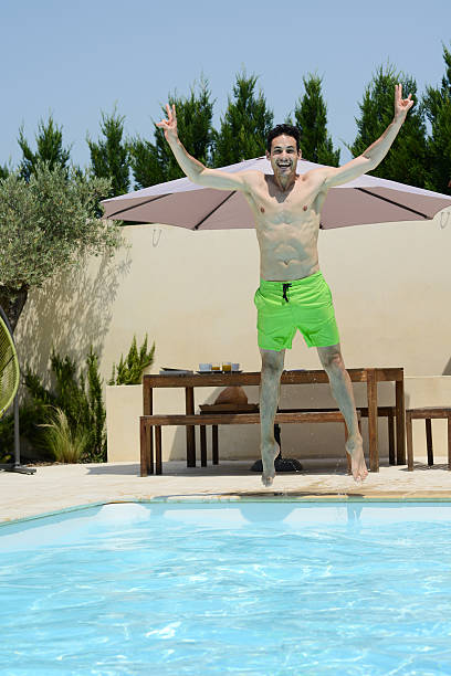 istock handsome young man jumping in the swimming pool 482074786
