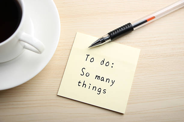 To do A yellow sticky note is written something on the desk with a cup of coffee and a ball pen aside. managing stress stock pictures, royalty-free photos & images