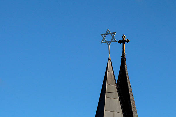 Side by side spires with cross and star of david Perspective of church and synagogue spires atopped with a cross and Star of David.  The two spires appear to be overlapping in a clear sky. synagogue photos stock pictures, royalty-free photos & images