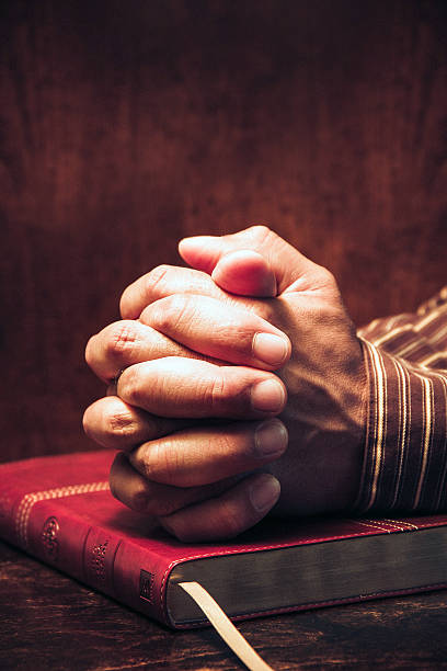 istock Praying with hands together in a Bible 482091756