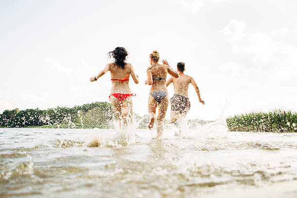 istock young adults running into lake, water splashes 482096370
