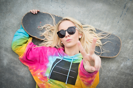 Pretty blond skater girl giving peace sign