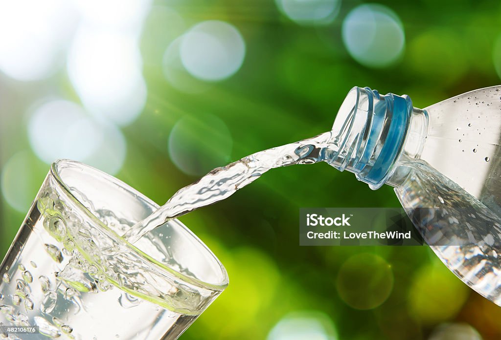 Drinking water is poured from a bottle into a glass Drinking water is poured from a bottle into a glassDrinking water is poured from a bottle into a glass Drinking Water Stock Photo