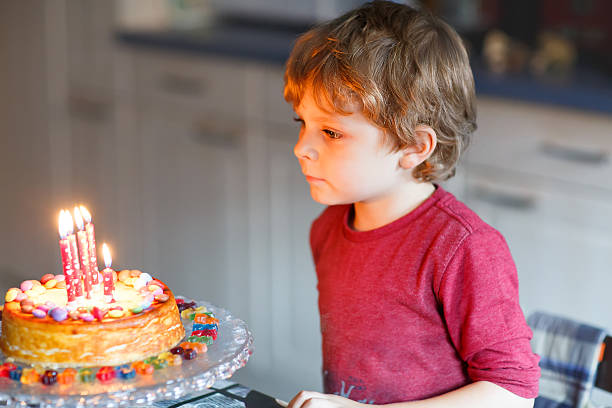 istock kid boy celebrating his birthday and blowing candles on cake 482106734