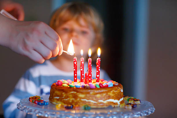 istock kid boy celebrating his birthday and blowing candles on cake 482111194