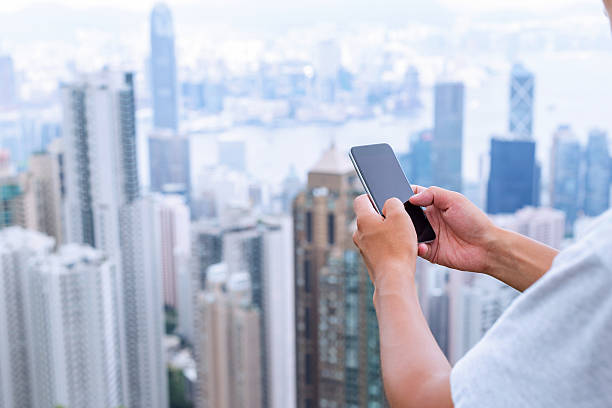istock hand holding mobile phone with cityscape as background 482113136