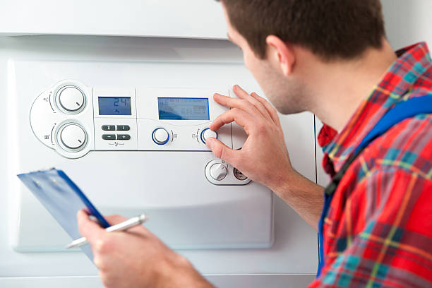 um homem em uma camisa de flanela trabalha uma caldeira a gás - heating engineer imagens e fotografias de stock