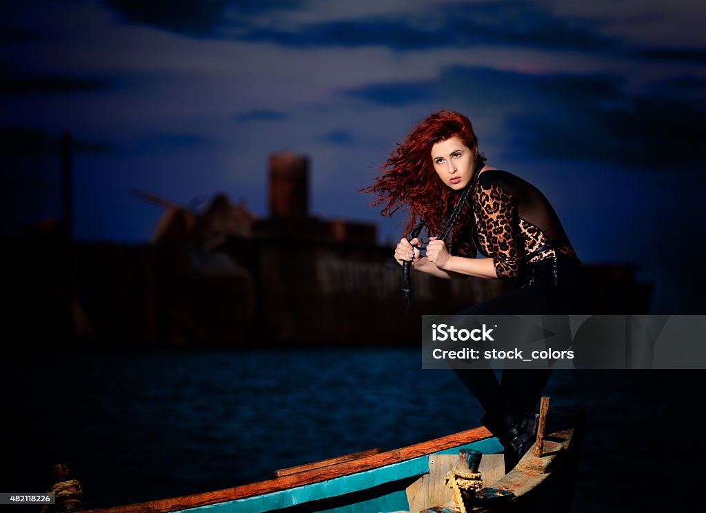 dramatic attractive woman sexy woman with leather whip on boat posing seductive, looking away and having sensual expression. Nautical Vessel Stock Photo