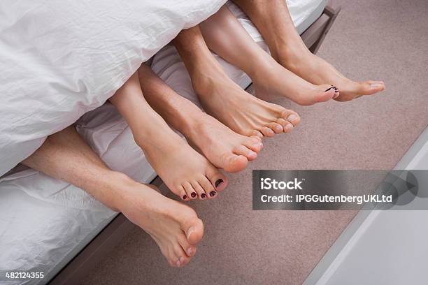 Low Section Of Woman With Two Men In Bed Stock Photo - Download Image Now - Three People, Bed - Furniture, Sensuality