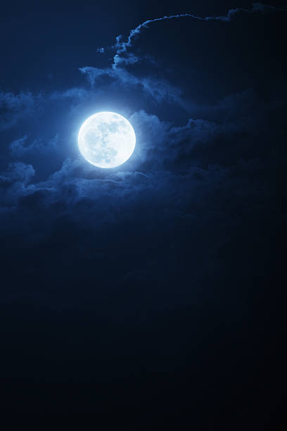 Dramatic Nighttime Clouds and Sky With Beautiful Full Blue Moon This dramatic photo illustration of a nighttime scene with brightly lit clouds and large, full, Blue Moon would make a great background for many uses. full moon stock pictures, royalty-free photos & images