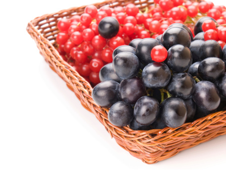 Fresh cranberries and grapes in basket isolated on white background