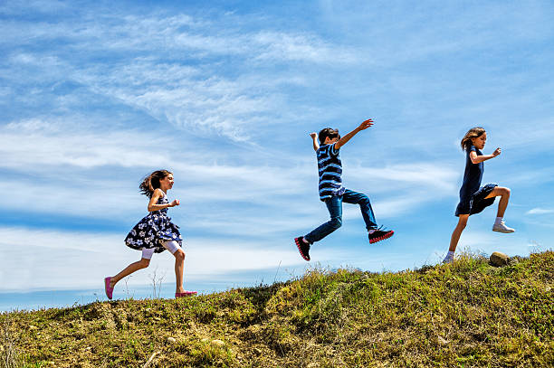 Children Playing Children skipping and jumping up a hill. skipping stock pictures, royalty-free photos & images