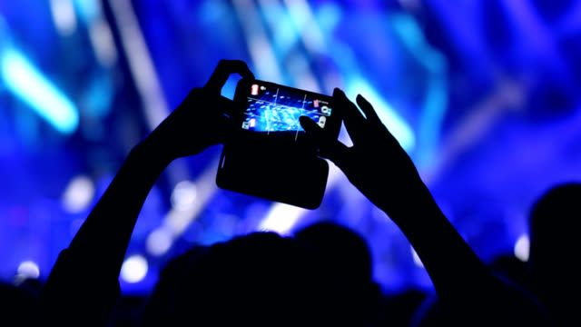Woman's hand holding a smart phone during a concert