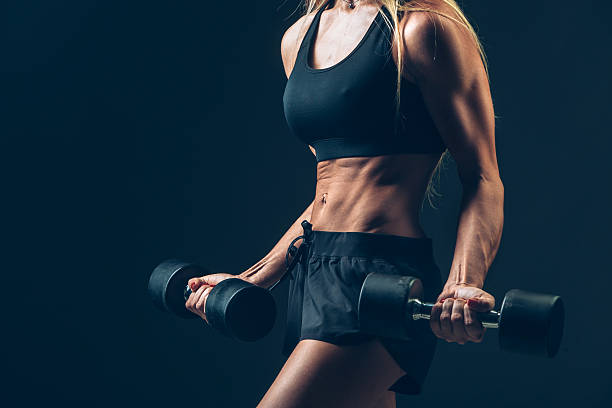 istock Athletic woman with dumbbells on a dark background 482145546
