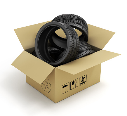 Open Cardboard Box with Tires on white background. Online store of auto parts.