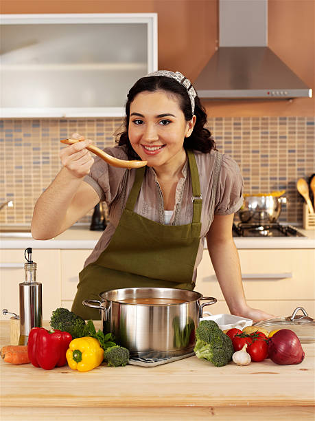 istock Young woman tasting soup in kitchen 482152232