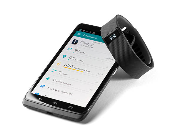 Fitbit charge with smartphone app Canton, GA, USA - July 24, 2015 A fitbit charge and a android smart phone with the fitbit app.  The fitbit is a fitness tracker capable of monitoring your steps per day, distance, stairs climbed, calories burned and also monitors your sleep activity. pedometer photos stock pictures, royalty-free photos & images